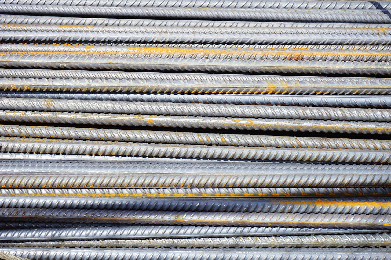 services-img Close-up of stacked rusty steel reinforcing bars used in construction.