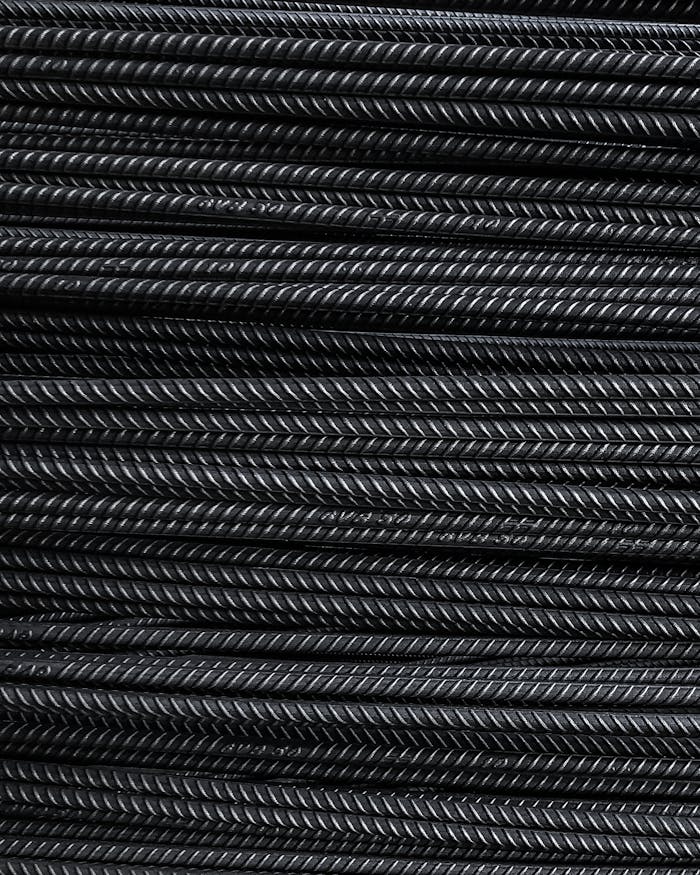services-02 Close-up view of neatly stacked metal rebars showcasing detailed texture and industrial feel.